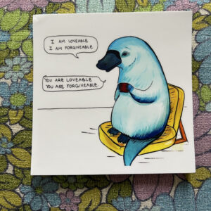 Blue platypus sits in chair holding tea. Says "I am loveable, I am forgiveable." "You are loveable, you are forgiveable"
